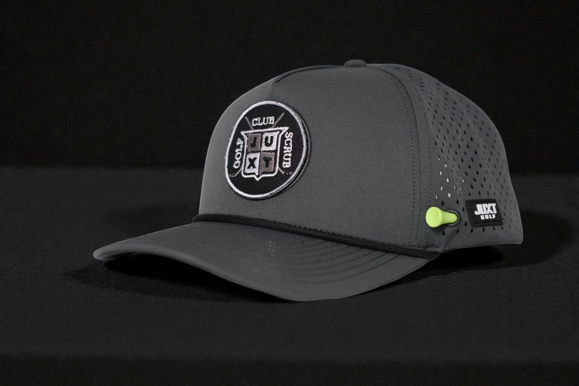 JUXT Golf Co. dark grey golf hat with a circular patch featuring 'GOLF CLUB SCRUB' and a neon green tee holder.